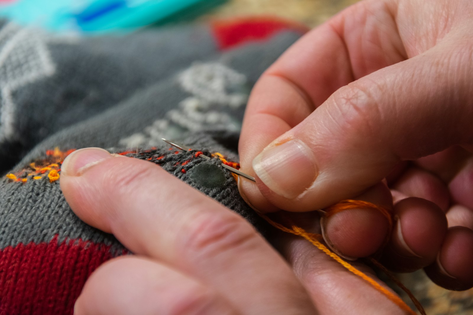 Aiguille en train de reprendre un trou de mite sur un pull